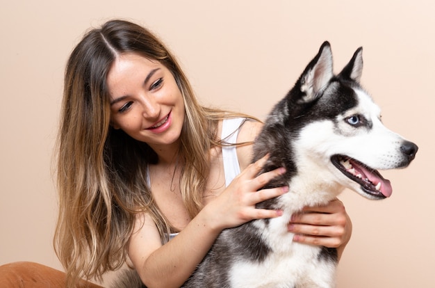 Mulher jovem e bonita com seu cachorro husky sentado no chão dentro de casa