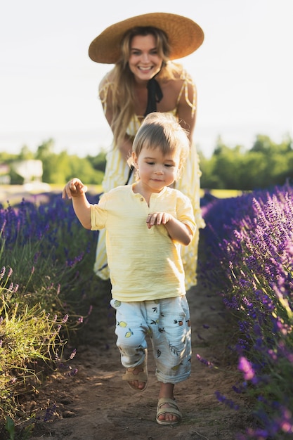 Mulher jovem e bonita com seu filho fofo em um campo de lavanda