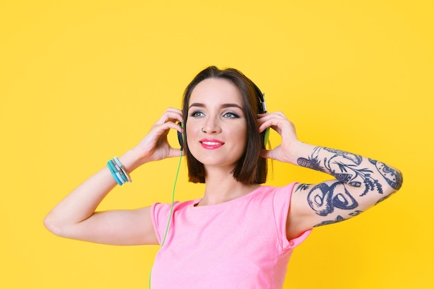 Mulher jovem e bonita com tatuagem usando fones de ouvido e posando