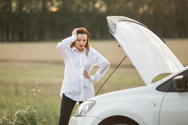 mulher jovem e bonita com telefone celular perto do carro