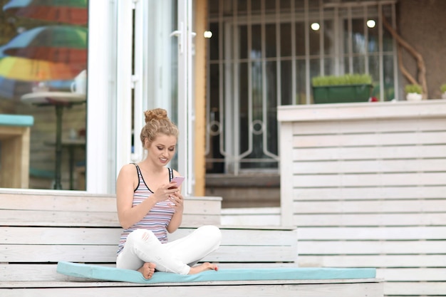 Mulher jovem e bonita com telefone móvel sentado na escada ao ar livre