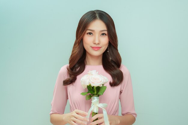 Mulher jovem e bonita com um buquê de flores de rosas em um fundo claro