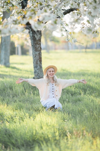 Mulher jovem e bonita com um chapéu de vime descansando em um piquenique em um jardim florido