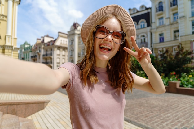 Mulher jovem e bonita com um chapéu tirando uma selfie
