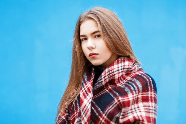 Mulher jovem e bonita com um lenço quente perto de uma parede azul