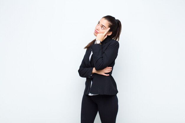 Mulher jovem e bonita com um olhar concentrado, pensando com uma expressão duvidosa, olhando para cima e para o lado conceito de negócio