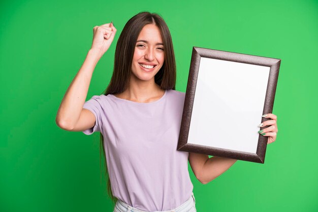 Foto mulher jovem e bonita com um porta-retrato vazio em branco