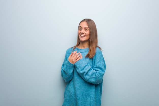 Mulher jovem e bonita com um suéter azul fazendo um gesto romântico