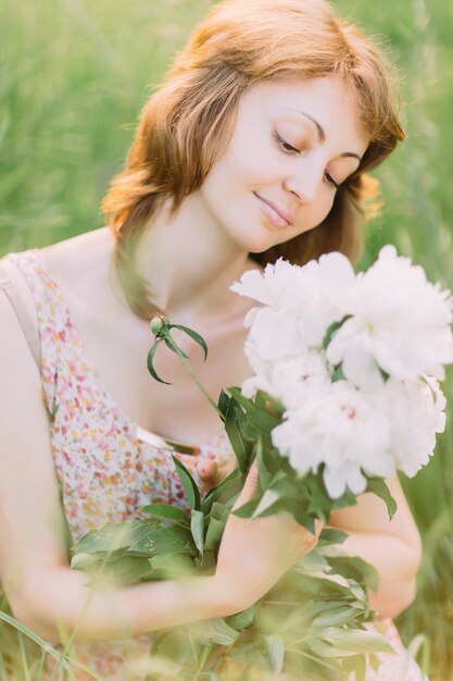 Mulher jovem e bonita com um vestido de verão com peônias