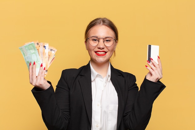 Mulher jovem e bonita com uma expressão feliz e surpresa segurando dinheiro