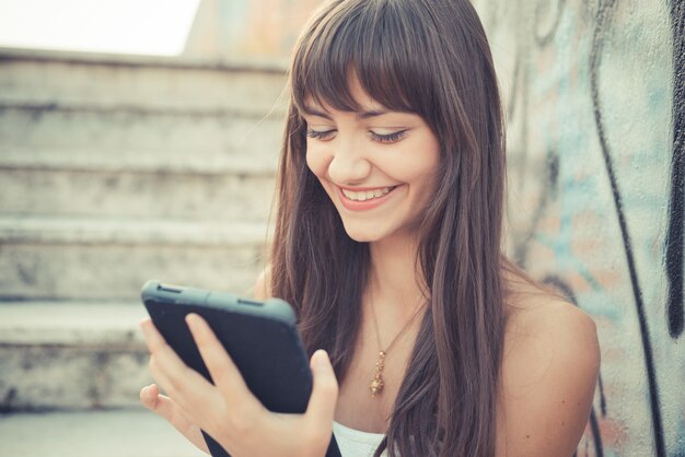 mulher jovem e bonita com vestido branco usando tablet