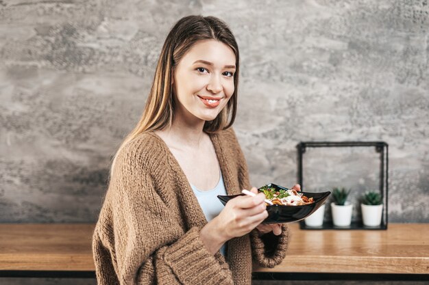 Mulher jovem e bonita comendo massa italiana.