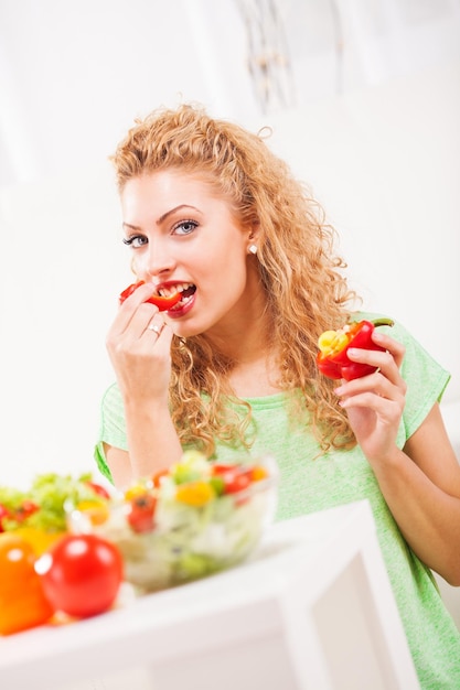 Mulher jovem e bonita comendo pimenta na sala de estar