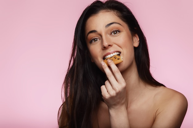 Mulher jovem e bonita comendo um biscoito