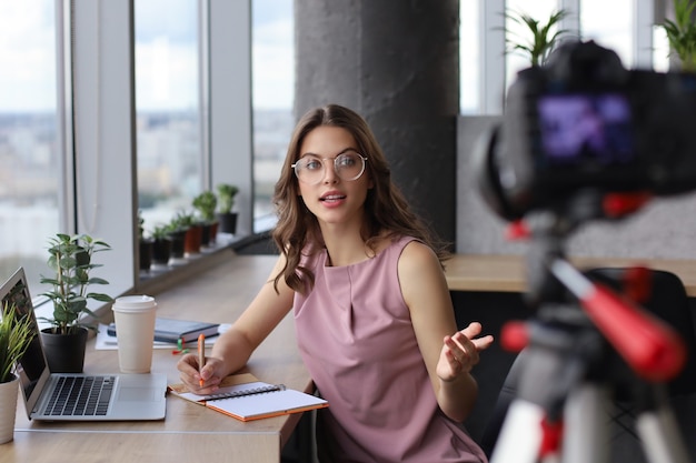 Foto mulher jovem e bonita conversando e sorrindo enquanto faz um novo vídeo para seu blog.