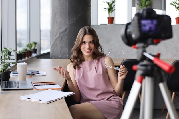 Mulher jovem e bonita conversando e sorrindo enquanto faz um novo vídeo para seu blog.
