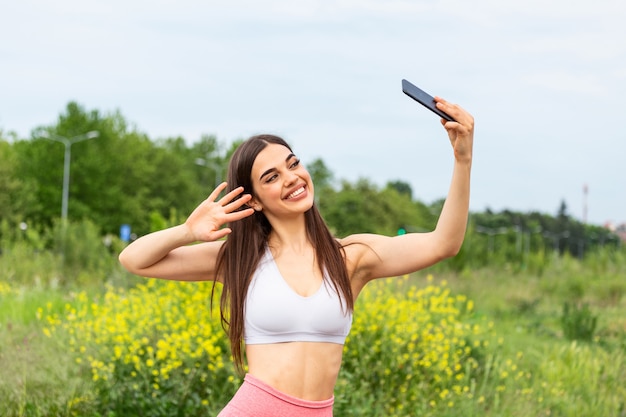 Mulher jovem e bonita correndo na corrida da cidade tomando uma selfie