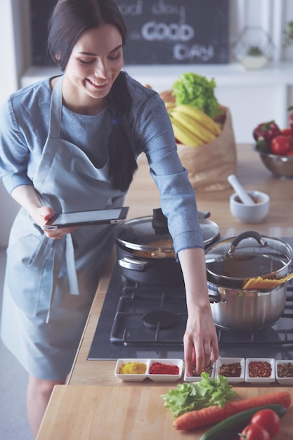 Mulher jovem e bonita cozinhando na cozinha em casa.