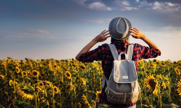 Mulher jovem e bonita curtindo a natureza no campo de girassóis ao pôr do sol