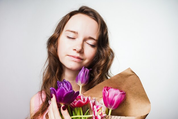 Mulher jovem e bonita curtindo a primavera, segurando um buquê de flores perfumadas e esperando o dia mundial da mulher