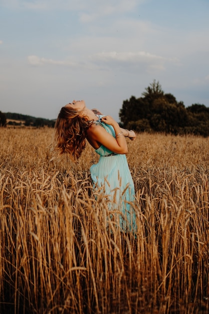 Mulher jovem e bonita dançando no campo ao pôr do sol