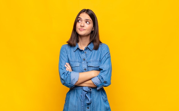 Mulher jovem e bonita dando de ombros, sentindo-se confusa e insegura