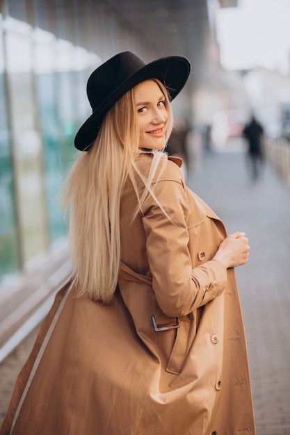 Mulher jovem e bonita de chapéu preto e casaco bege caminhando pelo shopping