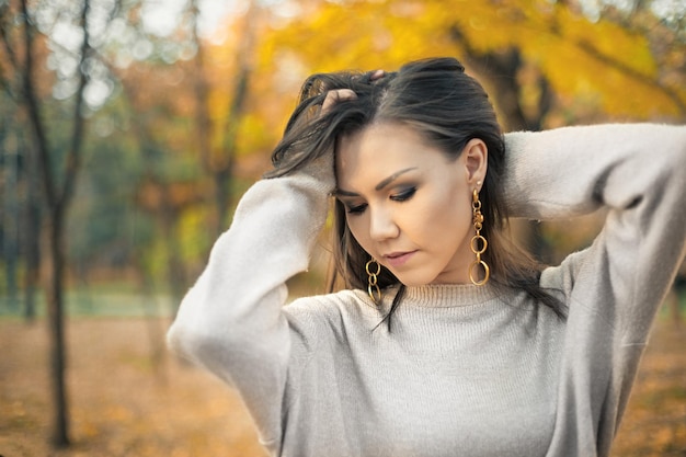 Mulher jovem e bonita de raça mista moda roupas de outono suéter cinza no outono ao ar livre