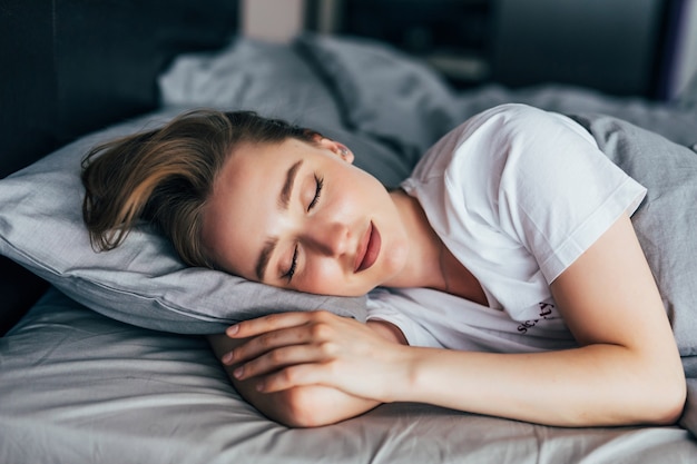 Mulher jovem e bonita deitada e dormindo em sua cama em casa