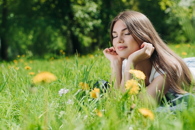 Mulher jovem e bonita deitada na grama com flores dente de leão no parque