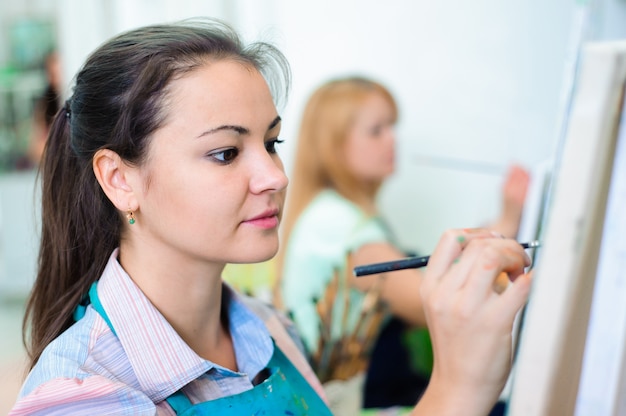 Mulher jovem e bonita desenha pinturas na aula de arte