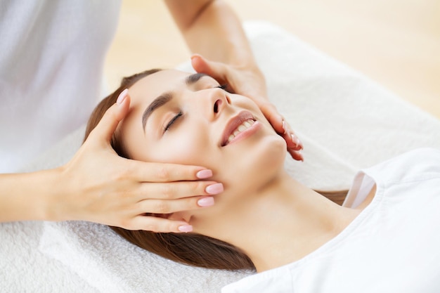 Mulher jovem e bonita, desfrutando de procedimento de massagem facial.