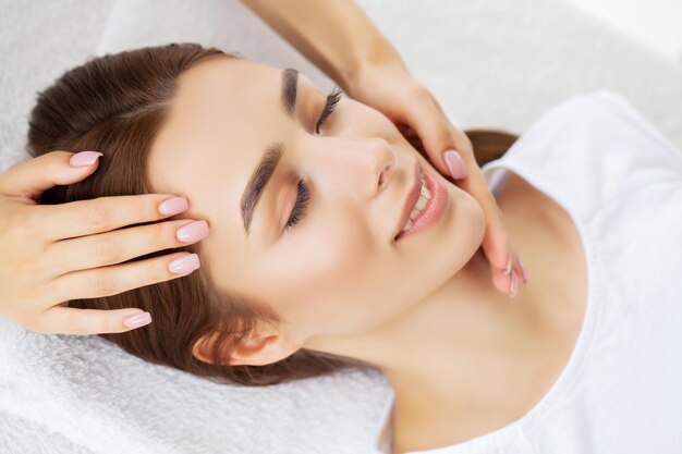 Mulher jovem e bonita, desfrutando de procedimento de massagem facial.