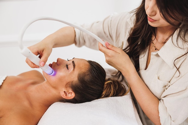 Mulher jovem e bonita desfrutando de um tratamento hidrafacial no salão de beleza.