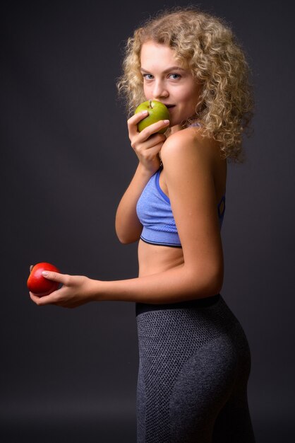 Mulher jovem e bonita do esporte pronta para a academia segurando uma maçã saudável