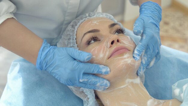 Mulher jovem e bonita durante procedimento cosmético em rosto realizado por médico especialista em salão de spa