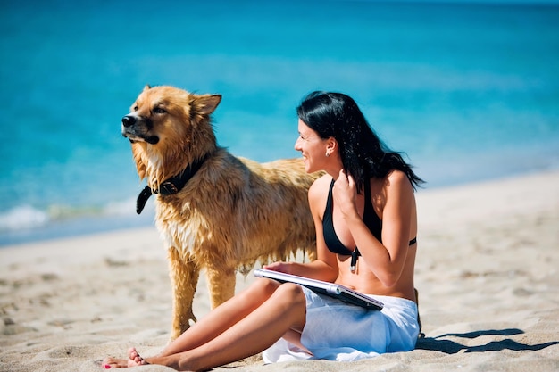 Mulher jovem e bonita e cachorro na praia