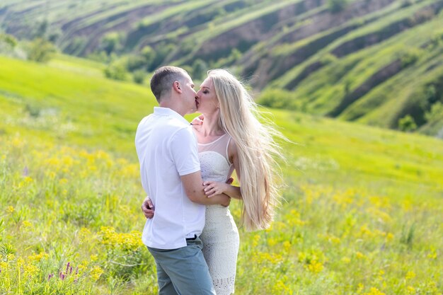 Mulher jovem e bonita e um homem andam, abraçam e se beijam na natureza ao pôr do sol.