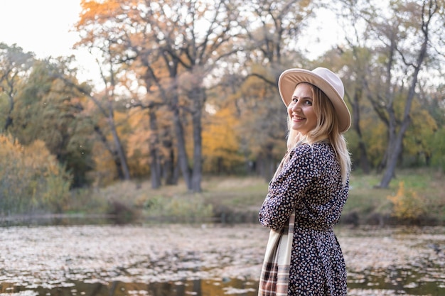 Mulher jovem e bonita elegante com chapéu caminha na natureza no parque outono no outono.