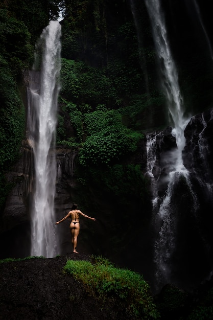 Mulher jovem e bonita em biquíni relaxante em frente a cachoeira. Ecoturismo conceito imagem viagens menina