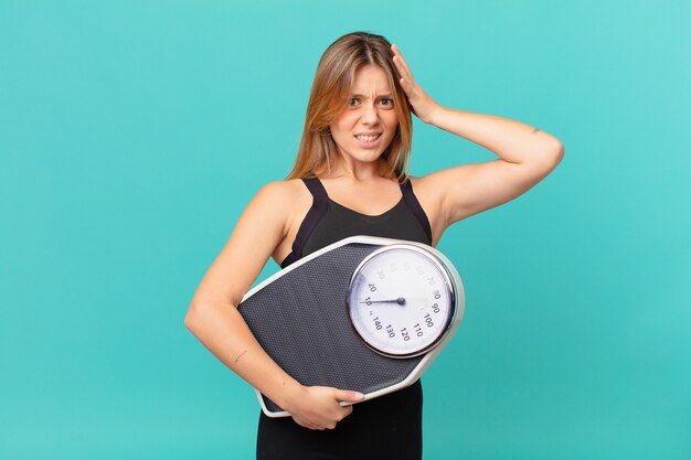 Mulher jovem e bonita em boa forma se sentindo estressada, ansiosa ou com medo, com as mãos na cabeça