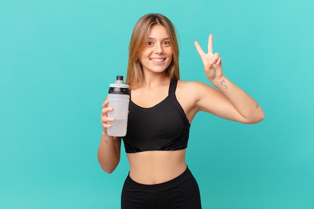 Mulher jovem e bonita em boa forma, sorrindo e parecendo amigável, mostrando o número dois