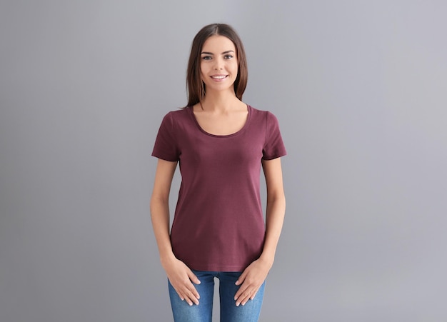 Mulher jovem e bonita em camiseta estilosa em fundo cinza Mockup para design