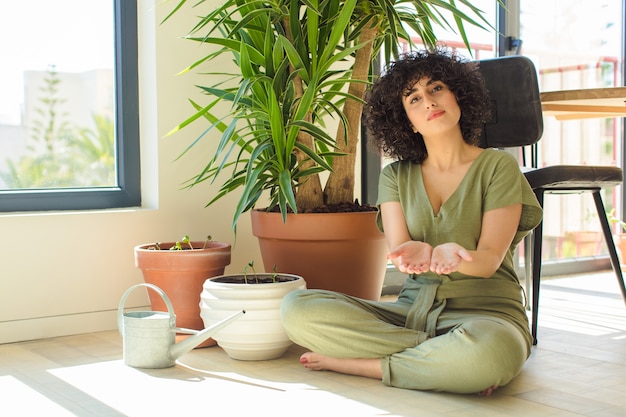 Foto mulher jovem e bonita em casa, com regador e plantas