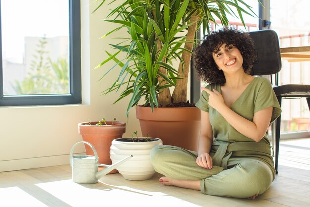 Foto mulher jovem e bonita em casa, com regador e plantas