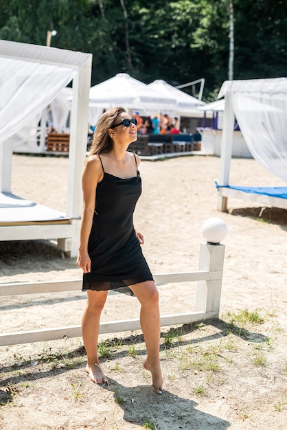 Mulher jovem e bonita em pé perto do gazebo branco dia de verão