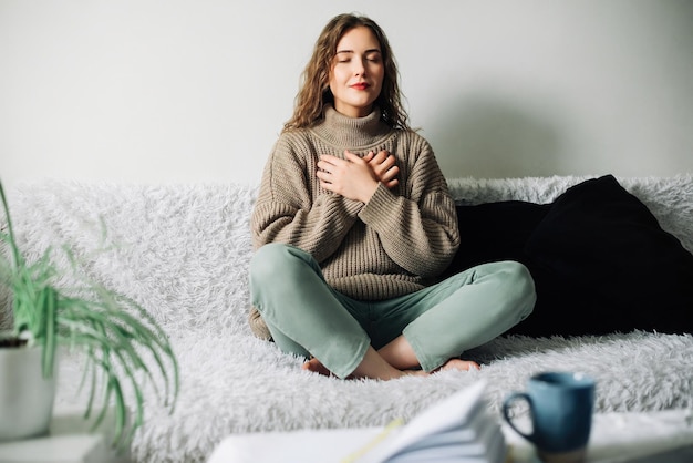 Mulher jovem e bonita em pose de lótus na cama praticando técnicas de respiração pranayama encontrando interior