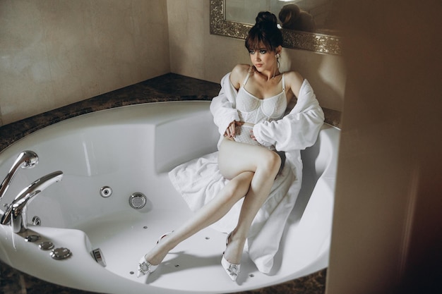 Mulher jovem e bonita em roupão de banho sentado no banho Conceito de autocuidado