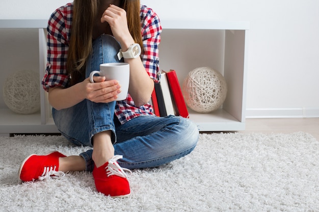 Mulher jovem e bonita em roupas casuais modernas, sentado no chão