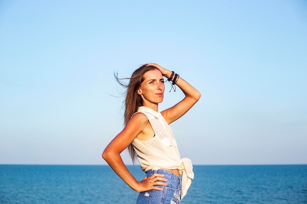 Mulher jovem e bonita em shorts jeans e camisa para o mar.